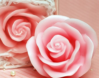 May include: Two pink rose-shaped candles in a gift box. The candles are made of wax and have a realistic rose design.