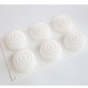 K&ouml;nnte beinhalten: Eine wei&szlig;e Silikonform mit sechs kreisf&ouml;rmigen Vertiefungen, jede mit einem Spiraldesign. Die Form ist rechteckig mit abgerundeten Ecken und f&uuml;r das Backen oder Basteln konzipiert. Die Gesamt&auml;sthetik ist sauber und minimalistisch.