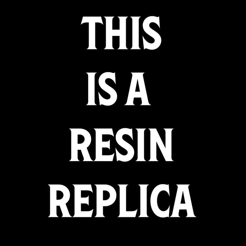 May include: Black background with the white text "THIS IS A RESIN REPLICA" in a bold, serif font. The text is centered and takes up most of the image.