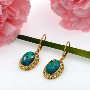 May include: A pair of gold dangle earrings with oval turquoise blue stones set in a filigree design.