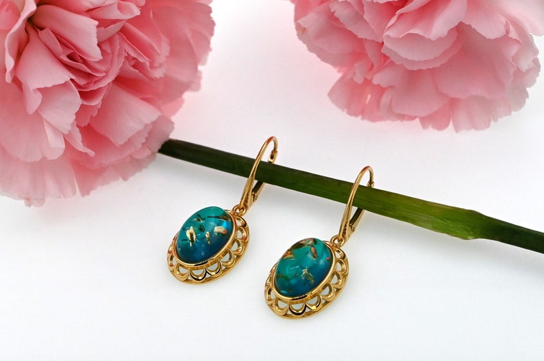 May include: A pair of gold dangle earrings with oval turquoise blue stones set in a filigree design.