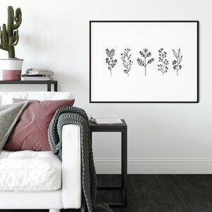 May include: Black and white line art print of five different floral sprigs with small flowers and leaves. The print is framed in a black frame and hanging on a white wall.