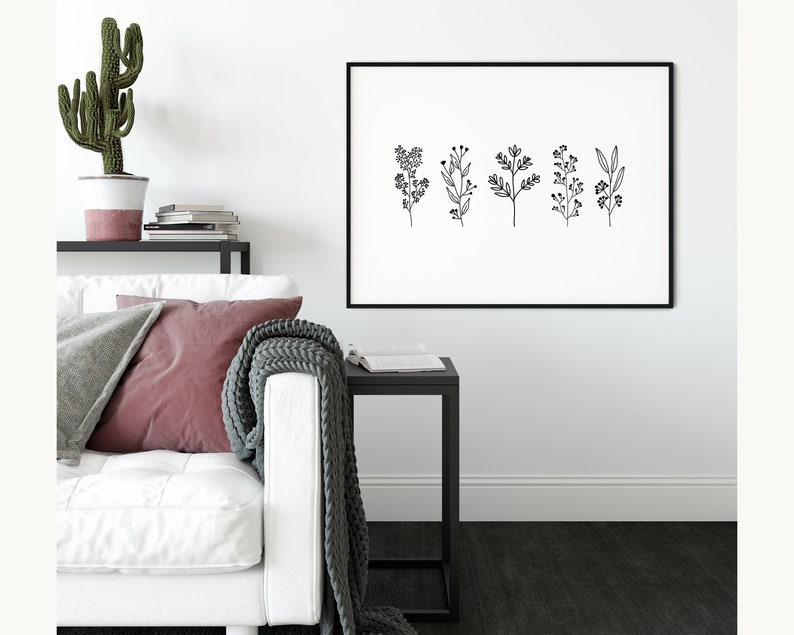 May include: Black and white line art print of five different floral sprigs with small flowers and leaves. The print is framed in a black frame and hanging on a white wall.