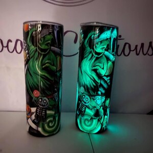 May include: Two glow-in-the-dark tumblers with a green and black design featuring the character Jack Skellington from the movie The Nightmare Before Christmas.