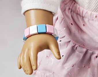 May include: A bracelet made of square-shaped beads in pink, white and blue colours.