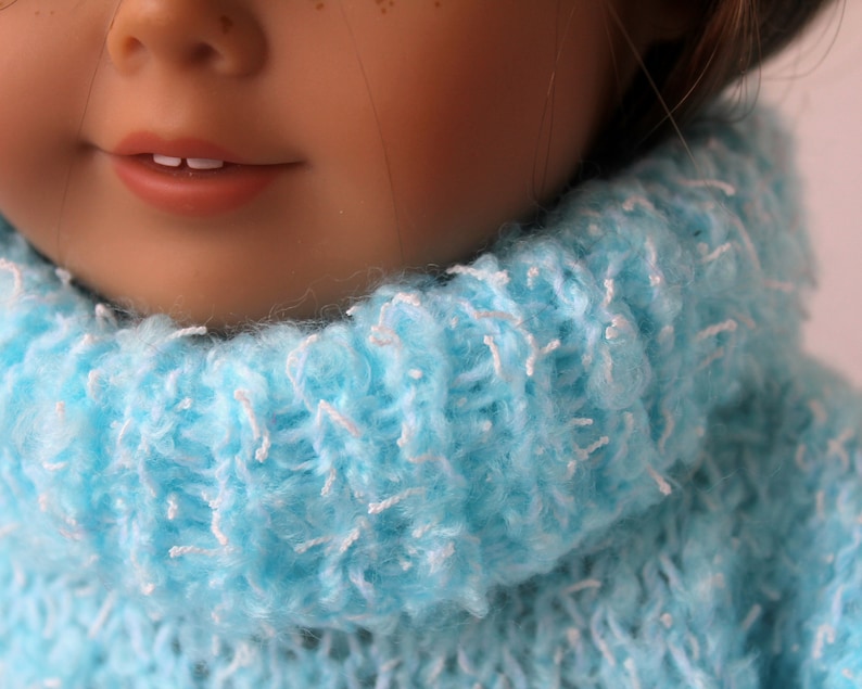 May include: A close-up of a doll wearing a light blue fuzzy turtleneck sweater.