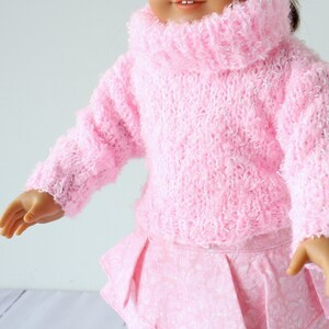 May include: A pink fuzzy sweater with a turtleneck and long sleeves. The sweater is made of a soft, fluffy yarn.