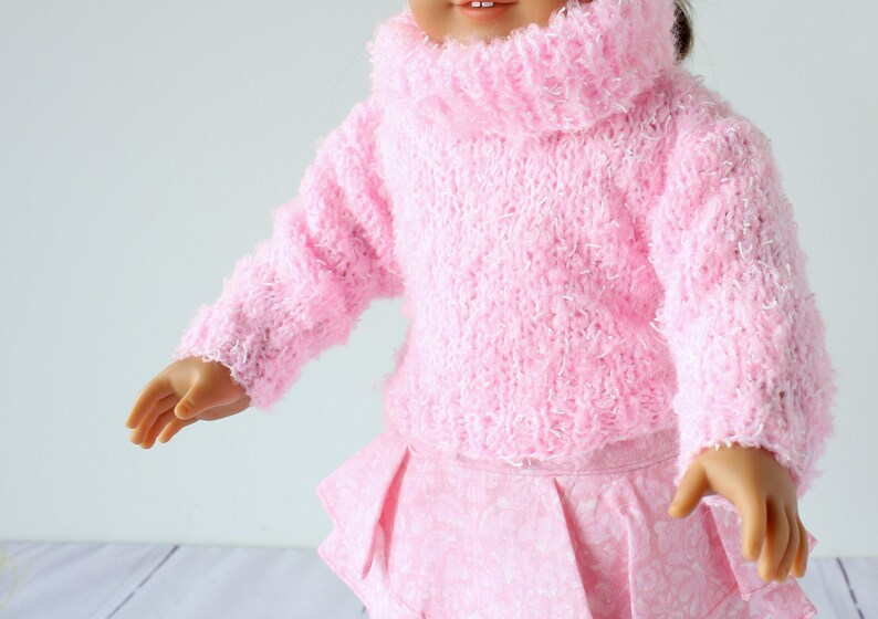 May include: A pink fuzzy sweater with a turtleneck and long sleeves. The sweater is made of a soft, fluffy yarn.