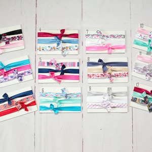 May include: Twelve sets of three hair ties, each set featuring different patterned and solid coloured hair ties. The hair ties are arranged on white cards with numbers 1 through 12.