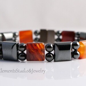 May include: A bracelet made of alternating carnelian and hematite beads. The carnelian beads are square and have a reddish-orange color. The hematite beads are round and black.