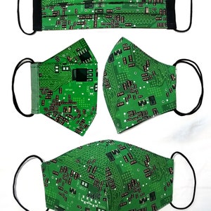 Puede incluir: Cinco mascarillas verdes con un patr&oacute;n de placa de circuito. Las mascarillas tienen lazos el&aacute;sticos negros para las orejas.