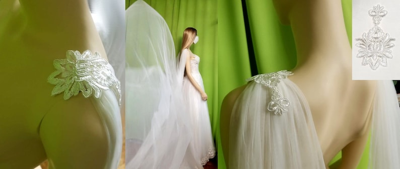 May include: A white tulle bridal veil with delicate lace trim. The veil is draped over a mannequin's shoulders and has a scalloped edge.