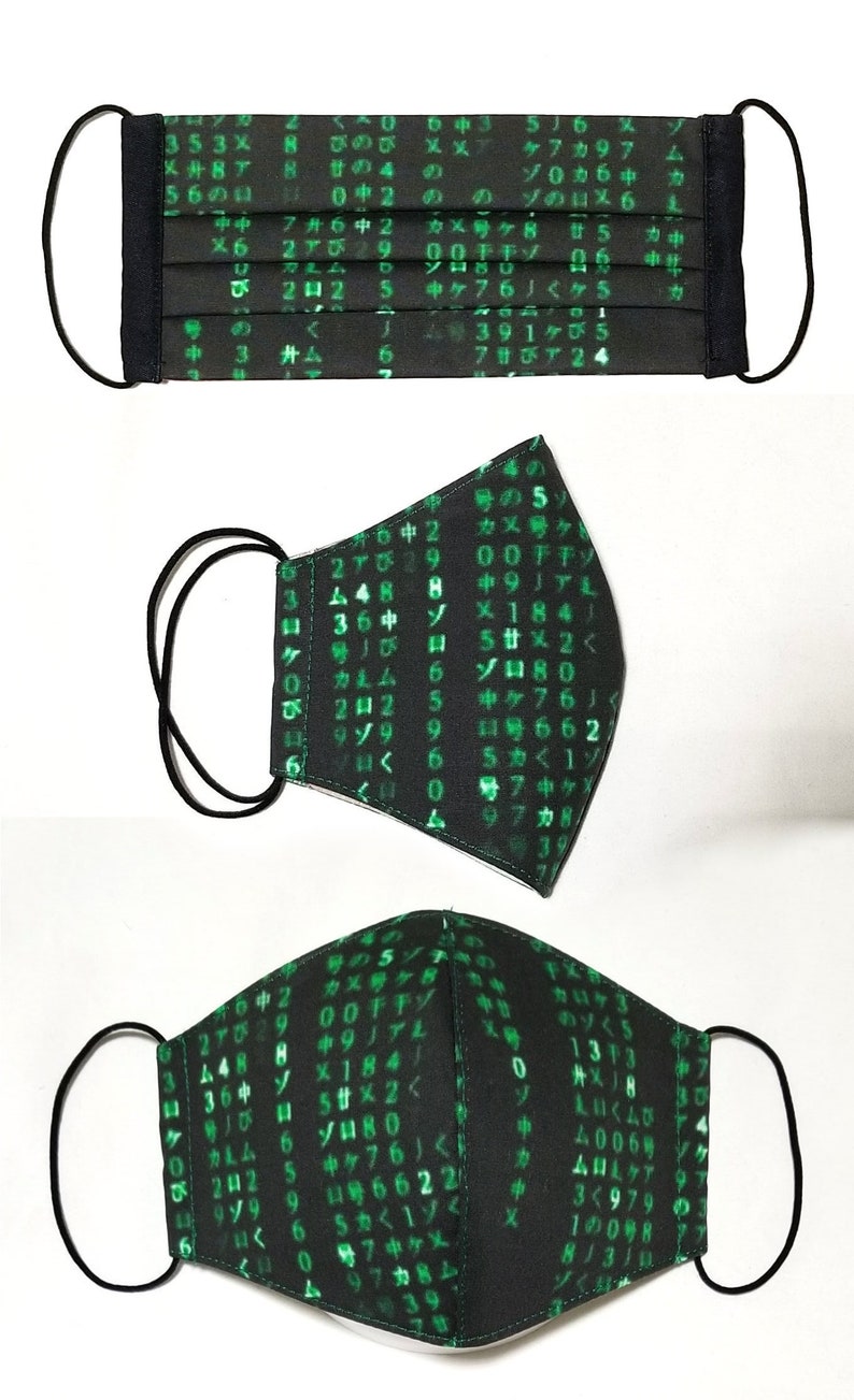Puede incluir: M&aacute;scara facial negra con texto y n&uacute;meros verdes, que se asemejan a un c&oacute;digo inform&aacute;tico. La m&aacute;scara tiene lazos el&aacute;sticos para las orejas.