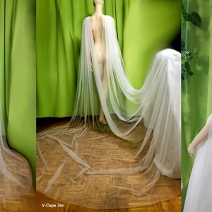 May include: Two white tulle capes, one 2 meters long and one 3 meters long, shown on mannequins. The capes are sheer and flowy, with a V-neckline.