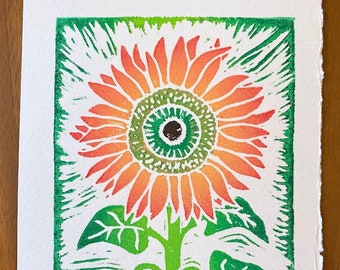 May include: A green and orange linocut print of a sunflower. The print is titled "Sunflowers" and signed "Joreh Hess". The print is numbered 49/50.
