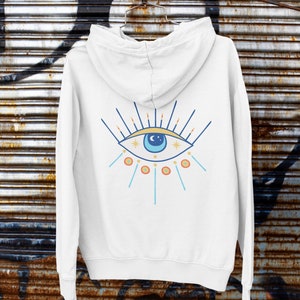 May include: White hooded sweatshirt with a blue eye graphic on the back. The eye has a yellow crescent moon and stars inside. The eye is surrounded by orange and blue rays.