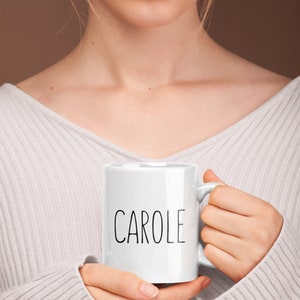 May include: White ceramic mug with the name "CAROLE" printed in black lettering.