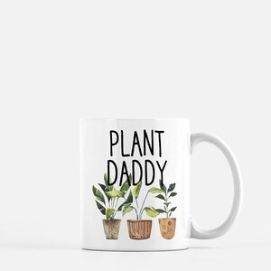 May include: White ceramic mug with a black graphic that says "Plant Daddy" and three potted plants with green leaves.