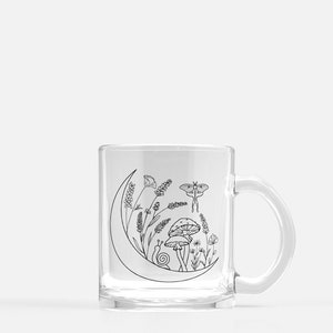May include: A clear glass mug with a black line drawing of a crescent moon, flowers, a mushroom, a snail, and a moth. The design is on the front of the mug.