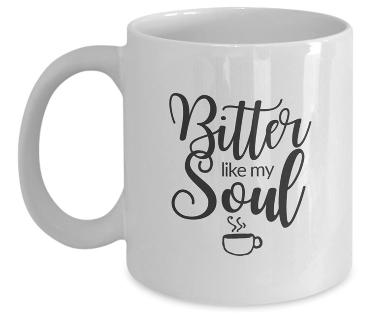Op de afbeelding: Witte keramische koffiemok met zwarte tekst die "Bitter like my Soul" luidt en een kleine zwart-witte illustratie van een koffiekopje met stoom die eruit opstijgt.
