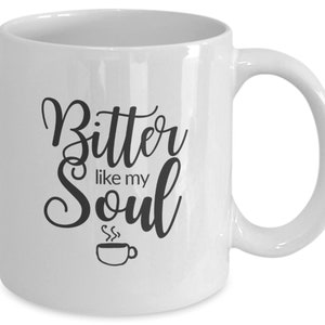 Op de afbeelding: Witte keramische koffiemok met zwarte tekst die "Bitter like my Soul" luidt en een klein zwart koffiekopje-icoon.