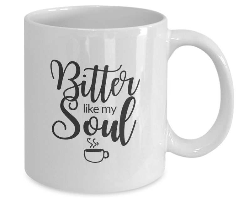 Op de afbeelding: Witte keramische koffiemok met zwarte tekst die "Bitter like my Soul" luidt en een klein zwart koffiekopje-icoon.