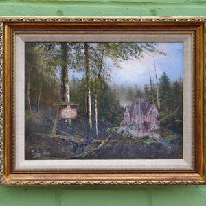 May include: An oil painting in a gold ornate frame depicts a forest scene with a pink house and a sign. The painting features a house with a porch, trees, and a sign with text. The artwork is framed in a gold-colored frame.