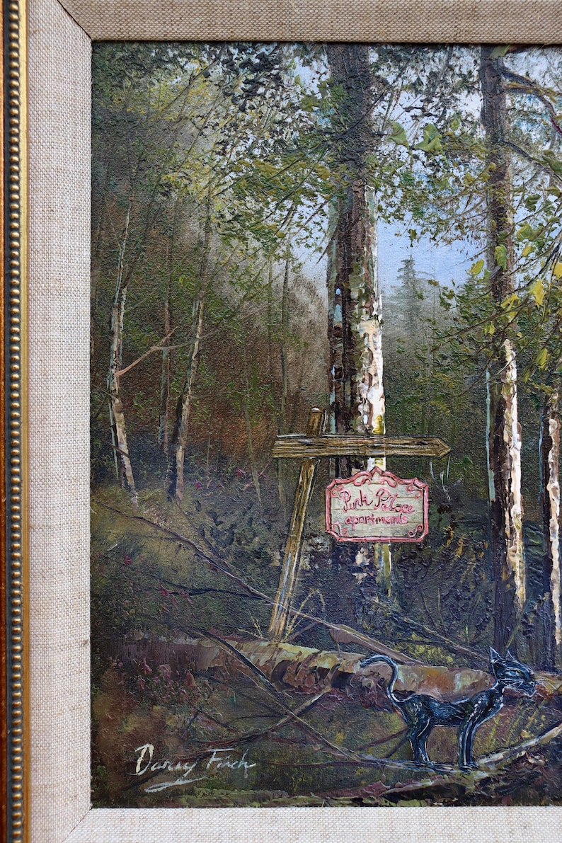 May include: Oil painting of a forest scene with a sign that reads "Pink Palace apartments." A black cat sculpture is in the foreground. The painting is in a gold-colored frame.