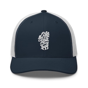 Könnte beinhalten: Eine marineblaue Baseballkappe mit weißem Netzrücken und strukturiertem Vorderteil. Auf der Vorderseite befindet sich eine weiße Stickerei in Form des Lake Tahoe, wobei die Worte Lake Tahoe in das Design der Seeumrisse integriert sind.