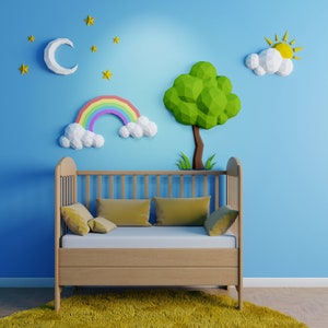 Puede incluir: Una cuna de madera con una pared azul claro detrás. La pared está decorada con recortes de papel de un arcoíris, una luna, estrellas, un árbol y un sol. La cuna tiene un colchón blanco y almohadas amarillas.