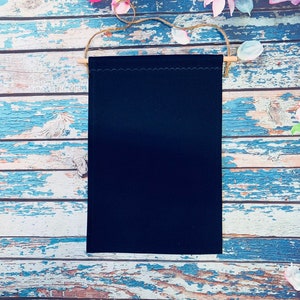 May include: A black felt banner with a scalloped edge, hanging from a wooden dowel with twine.