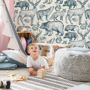 May include: A child plays in a teepee tent in a room with a wallpaper featuring a blue and white woodland animal print. The wallpaper features bears, deer, foxes, and other animals.
