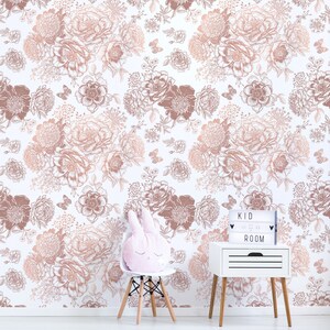 May include: A white wall with a rose gold floral pattern wallpaper. A white bedside table with a light box that says "KID ROOM" is on the right side of the image. A white chair with a pink bunny rabbit cushion is on the left side of the image.