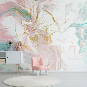 Puede incluir: Un papel tapiz abstracto de mármol rosa y turquesa con detalles dorados. El papel tapiz está en una habitación con una silla blanca y un armario blanco.