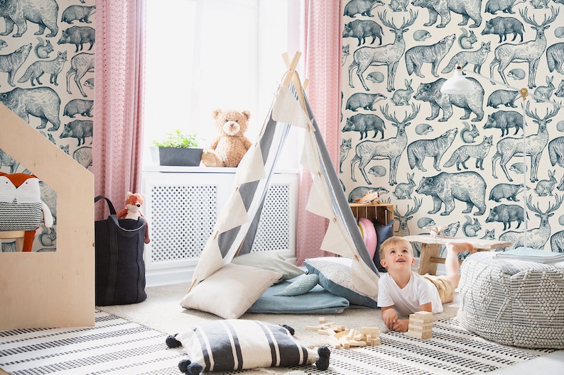 May include: A child plays in a teepee tent in a room with a wallpaper featuring a blue and white woodland animal print. The wallpaper features bears, deer, foxes, and other animals.