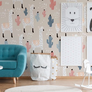 Puede incluir: Una habitaci&oacute;n infantil con un sof&aacute; turquesa, un balanc&iacute;n blanco y una mesa redonda blanca. Las paredes est&aacute;n decoradas con arte de animales enmarcados y un papel pintado beige con llamas y cactus en colores pastel. Dos bolsas de papel con ojos cerrados est&aacute;n en el suelo.