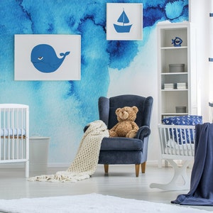 Puede incluir: Una habitaci&oacute;n de beb&eacute; con una pared con mural de acuarela azul que presenta una ballena y un velero. La habitaci&oacute;n tiene una cuna blanca, un mois&eacute;s mecedor, un sill&oacute;n azul con un oso de peluche y una estanter&iacute;a blanca con detalles azules.