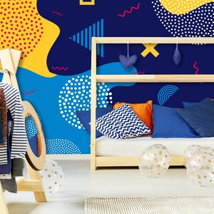 May include: A blue, yellow, and white geometric patterned wallpaper with a wooden bed frame and pillows. The bed frame has a shelf with blue and white heart-shaped decorations. There are clear balloons with gold stars on the floor.