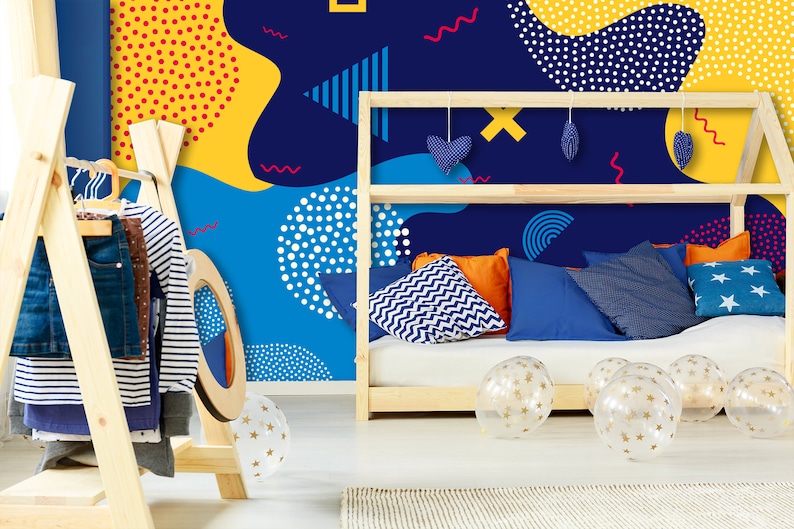 May include: A blue, yellow, and white geometric patterned wallpaper with a wooden bed frame and pillows. The bed frame has a shelf with blue and white heart-shaped decorations. There are clear balloons with gold stars on the floor.