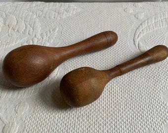 May include: Two wooden spoons, one with a rounded end and the other with a pointed end. Both spoons are brown and have a natural wood finish.