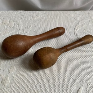 Könnte beinhalten: Zwei Holzlöffel, einer mit abgerundetem Ende und der andere mit spitzem Ende. Beide Löffel sind braun und haben eine natürliche Holzoptik.