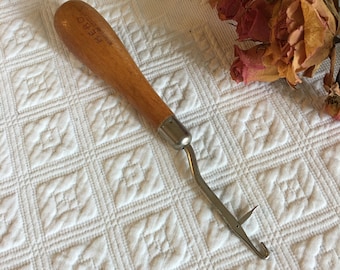 May include: A wooden crochet hook with a metal hook and a label that reads "F.R.O.S.T.  PAT.  PEND."