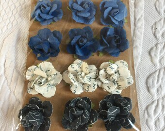 Craft Project 12 Dimensional Paper Flowers in Blue, White and Black. Glue Into Place. Small Bits of Green Leaves Show Around Edges.