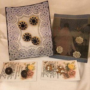 May include: An assortment of vintage earrings and decorative elements. Includes four pairs of black and gold earrings on a white lace-edged card, and two pairs of floral earrings on cards with text. A framed image with floral accents is also present.