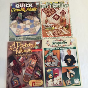 Puede incluir: Cuatro libros de patrones de acolchado con cubiertas coloridas. Los títulos son "Quick Candle Mats", "Nifty Nine-Patch Pot Holders", "A Pocketful of Whimsy" y "Simplicity Appliqués for a Green Thumb".