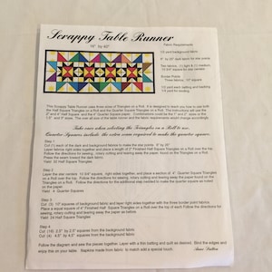 May include: Instructions for making a scrappy table runner measuring 16 inches by 40 inches. The instructions include a list of fabric requirements, a diagram of the finished product, and step-by-step instructions for cutting and sewing the fabric pieces.