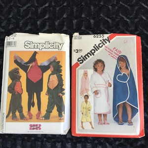 May include: Two vintage Simplicity sewing pattern packets. One features children's dinosaur and bird costumes. The other shows children's bathrobes and hooded towels. The patterns are in a variety of sizes.