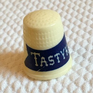 Vintage Size 8 Tastykake Advertising Thimble. Cream Plastic Thimble with Blue Banner Says Tastykake. Good for Sewing or Display.