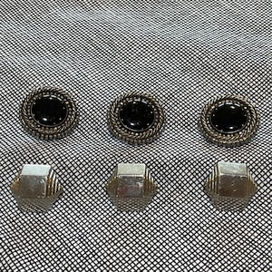 Może przedstawiać: Sześć zabytkowych srebrnych guzików. Trzy okrągłe guziki z czarnymi środkami i krawędziami w kształcie liny znajdują się nad trzema geometrycznymi, fasetowanymi guzikami. Guziki są na czarno-białej wzorzystej tkaninie.