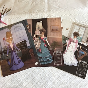 Puede incluir: Tres patrones de muñecas de ganchillo que presentan una muñeca con un vestido morado, una muñeca con un vestido verde azulado y una muñeca con un vestido rosa. Cada patrón incluye un calendario para enero, febrero y marzo.